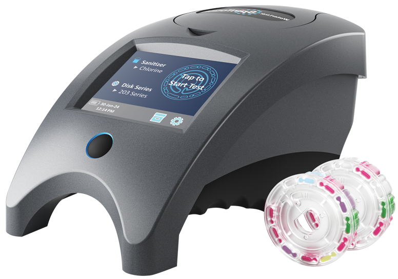 A compact, gray laboratory device with a digital display screen, shown next to two transparent plastic reagent discs containing colored segments for sample analysis.